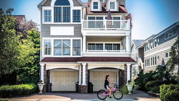 Een huis met twee verdiepingen, een balkon, een garage en een oprit.