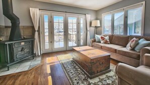 A living room with a fireplace, a sofa, a coffee table, and a view through a glass door. - GREAT OLD TOWN LOCATION- SKI TO TOWN LIFT & STEPS TO MAIN ST!  (Park City)