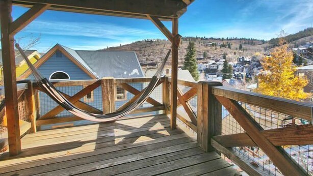 A wooden deck with a hammock, overlooking a town with houses and hills. - GREAT OLD TOWN LOCATION- SKI TO TOWN LIFT & STEPS TO MAIN ST!  (Park City)
