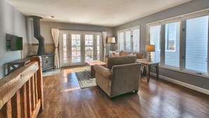 A spacious living room with hardwood flooring, a fireplace, a sofa, and large windows offering a view. - GREAT OLD TOWN LOCATION- SKI TO TOWN LIFT & STEPS TO MAIN ST!  (Park City)