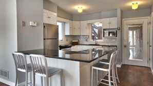 A modern kitchen with white cabinets, stainless steel appliances, and a central island with bar stools. - GREAT OLD TOWN LOCATION- SKI TO TOWN LIFT & STEPS TO MAIN ST!  (Park City)