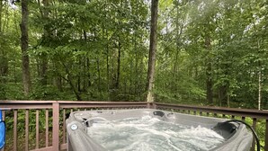 A hot tub on a wooden deck surrounded by a forest.