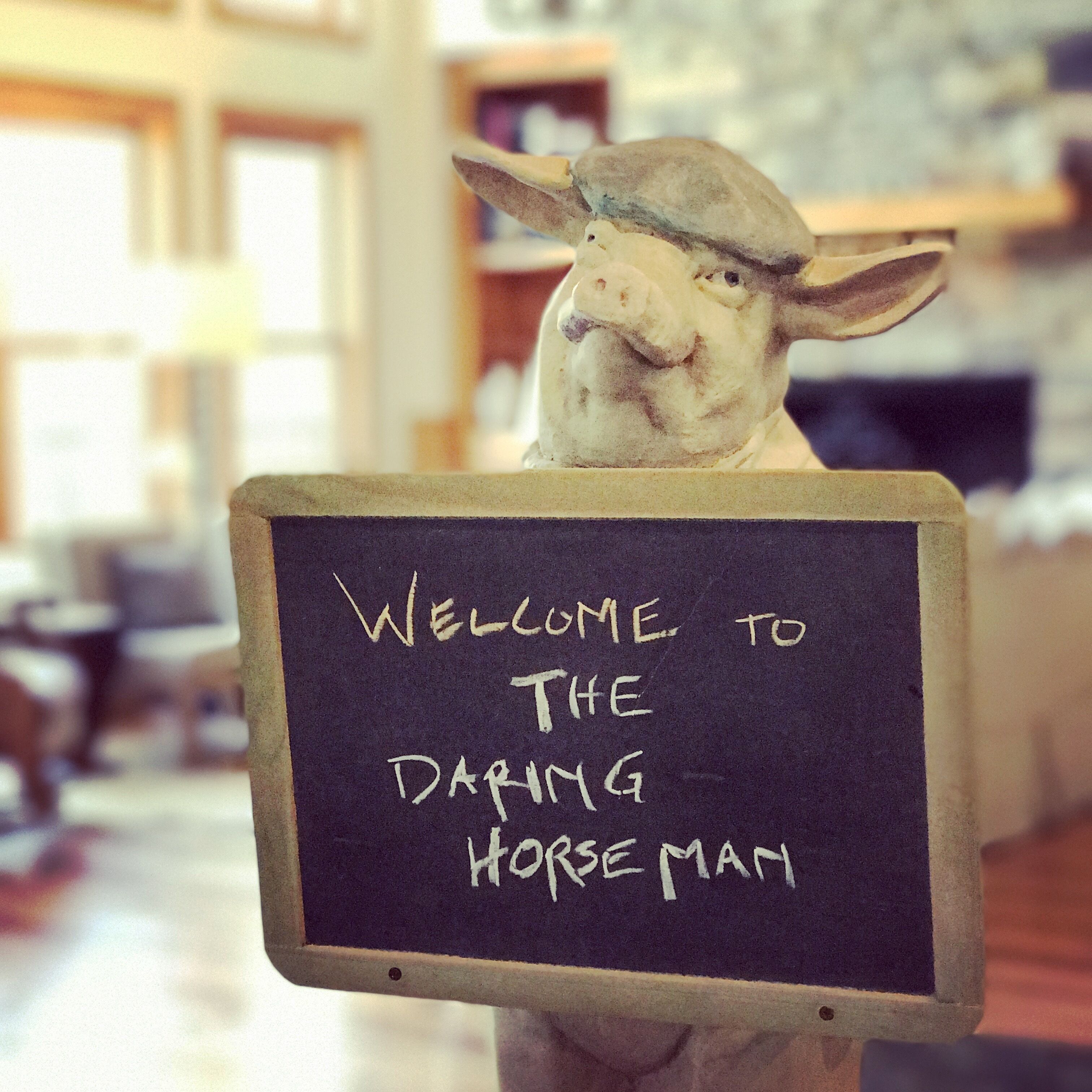 A sculpture of a horse holding a sign that reads "Welcome to the Daring Horse Man."