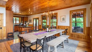 Een ruime eetruimte met een houten tafel, stoelen en een kroonluchter.