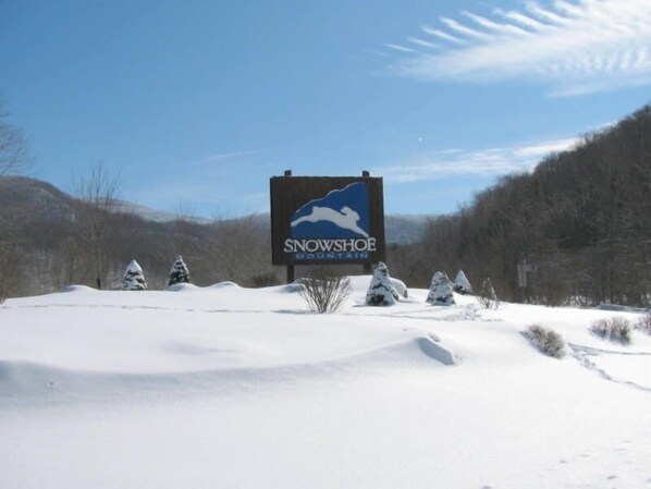 A snowy landscape with a sign for Snowshoe Mountain.