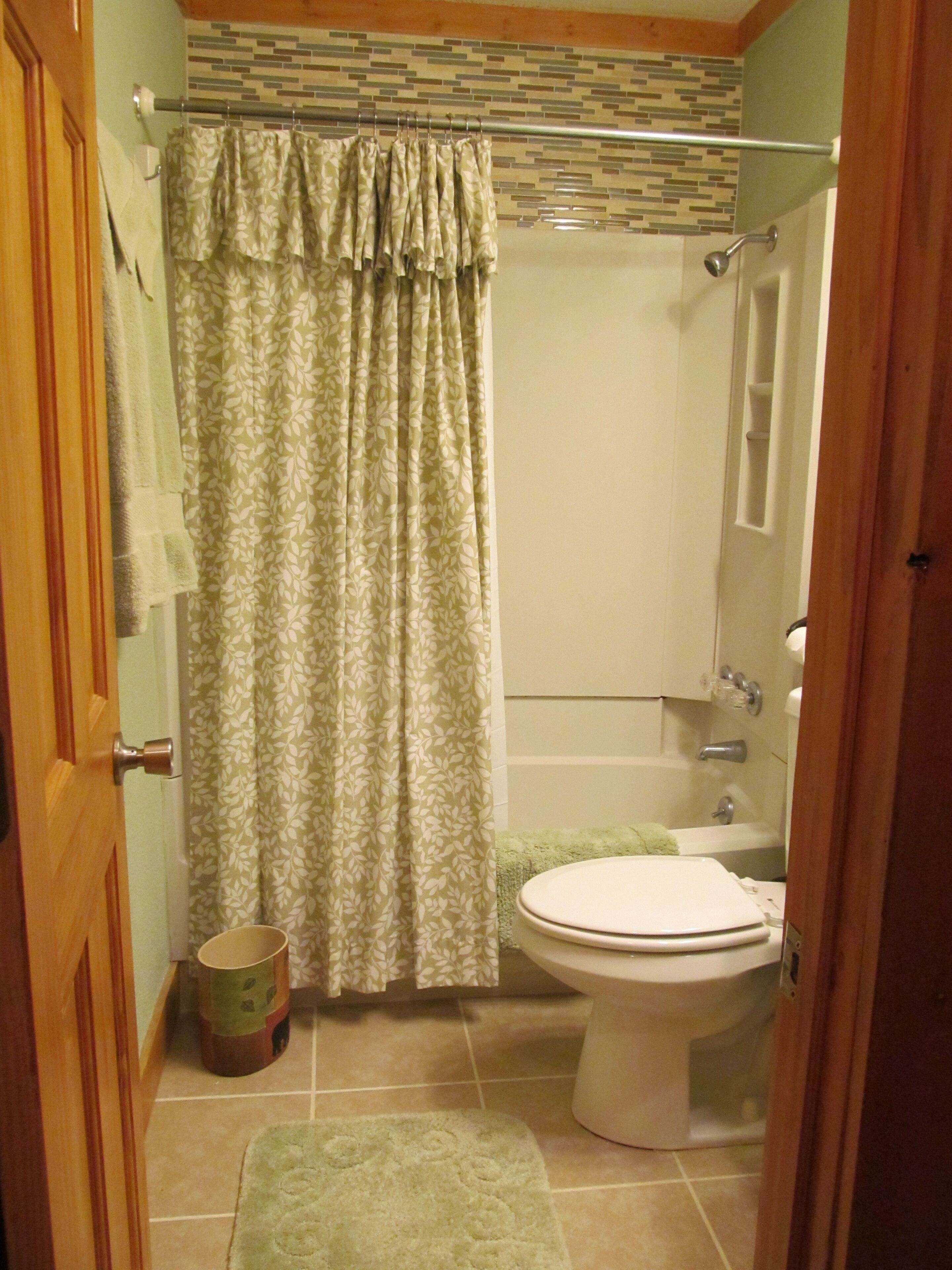 Une salle de bain avec des toilettes, une douche et un tapis vert.