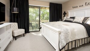 Ein Schlafzimmer mit einem großen Bett, einem weißen Schminktisch, einem Sessel und einem Deckenventilator.
