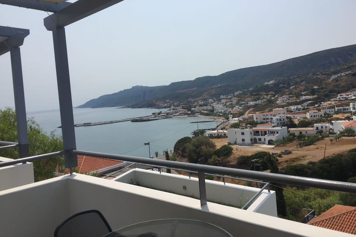 A balcony with a view of a coastal town, including buildings and a body of water.