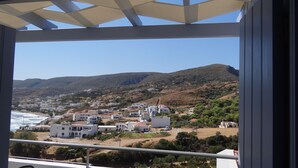 Un pueblo costero con edificios blancos, una playa y colinas al fondo.