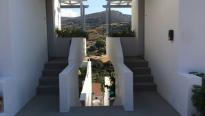 Diseño arquitectónico moderno con una escalera central que conduce a un balcón, con vistas a un paisaje montañoso.