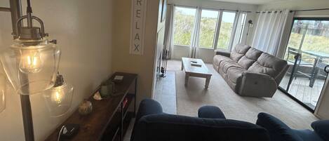 Un salon avec un canapé, une table basse et une lampe. Il y a une pancarte accrochée au mur sur laquelle on peut lire : « DÉTENTE ».