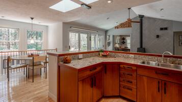 A modern kitchen with a wooden island, large windows, and a dining area with a view.