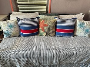 A bed with striped bedding and multiple pillows, including some with floral patterns.