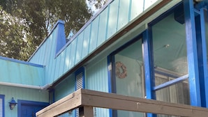 A wooden deck leading to a blue house with a front door and windows. - Unique Houseboat on Dry Lot-Perfect Romantic Getaway Or Family Friendly & Pet OK (Key Largo)