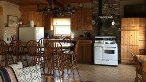 Una cocina acogedora con armarios de madera, una estufa y un comedor con sillas y una mesa.