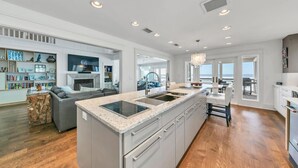 A spacious kitchen with a large island, a dining area with a view, and a living room with a fireplace.