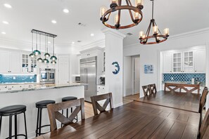 A modern kitchen with white cabinets, stainless steel appliances, and a central island with bar stools.