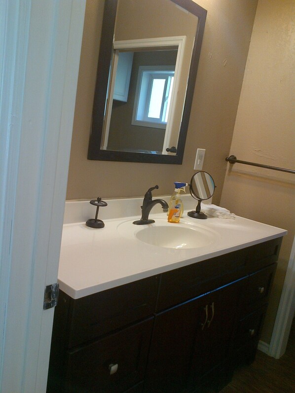 A bathroom with a white sink, dark brown cabinets, a mirror, and a towel rack. - Cozy Cottage, End-Of-Road Quiet, Woods, Piano! Great For Families (soldotna)