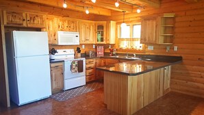 Una cocina con armarios de madera, un refrigerador, un microondas, una estufa y un lavamanos.