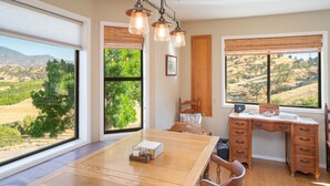 A room with a large desk, a dining table, and a view of a hilly landscape. - Ranch Getaway in the foothills of the Sierras (Springville)
