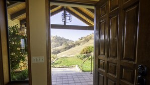 A wooden door leading to a tiled patio with a stone wall and a view of a hilly landscape. - Ranch Getaway in the foothills of the Sierras (Springville)