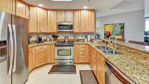 A modern kitchen with wooden cabinets, stainless steel appliances, granite countertops, and a skylight.