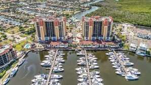 A marina with numerous boats docked, surrounded by residential buildings and a body of water.