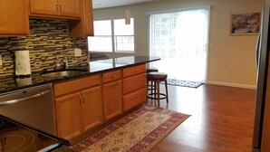A modern kitchen with wooden cabinets, a black countertop, and a patterned rug. - Richfield Charmer - Free WiFi and Close to MSP & Mall of America (Minneapolis)