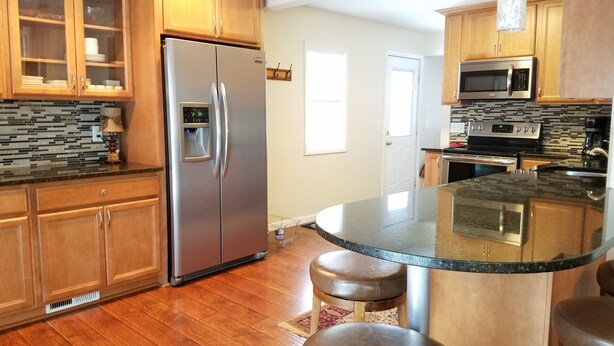 A kitchen with wooden cabinets, a stainless steel refrigerator, a microwave, and a granite countertop. - Richfield Charmer - Free WiFi and Close to MSP & Mall of America (Minneapolis)
