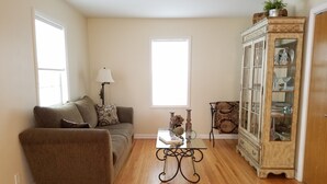 A living room with a sofa, a coffee table, a cabinet with glass doors, and a lamp. - Richfield Charmer - Free WiFi and Close to MSP & Mall of America (Minneapolis)