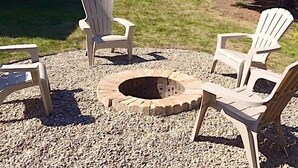 A backyard with a fire pit surrounded by Adirondack chairs, a wooden deck, and a house in the background. - Richfield Charmer - Free WiFi and Close to MSP & Mall of America (Minneapolis)