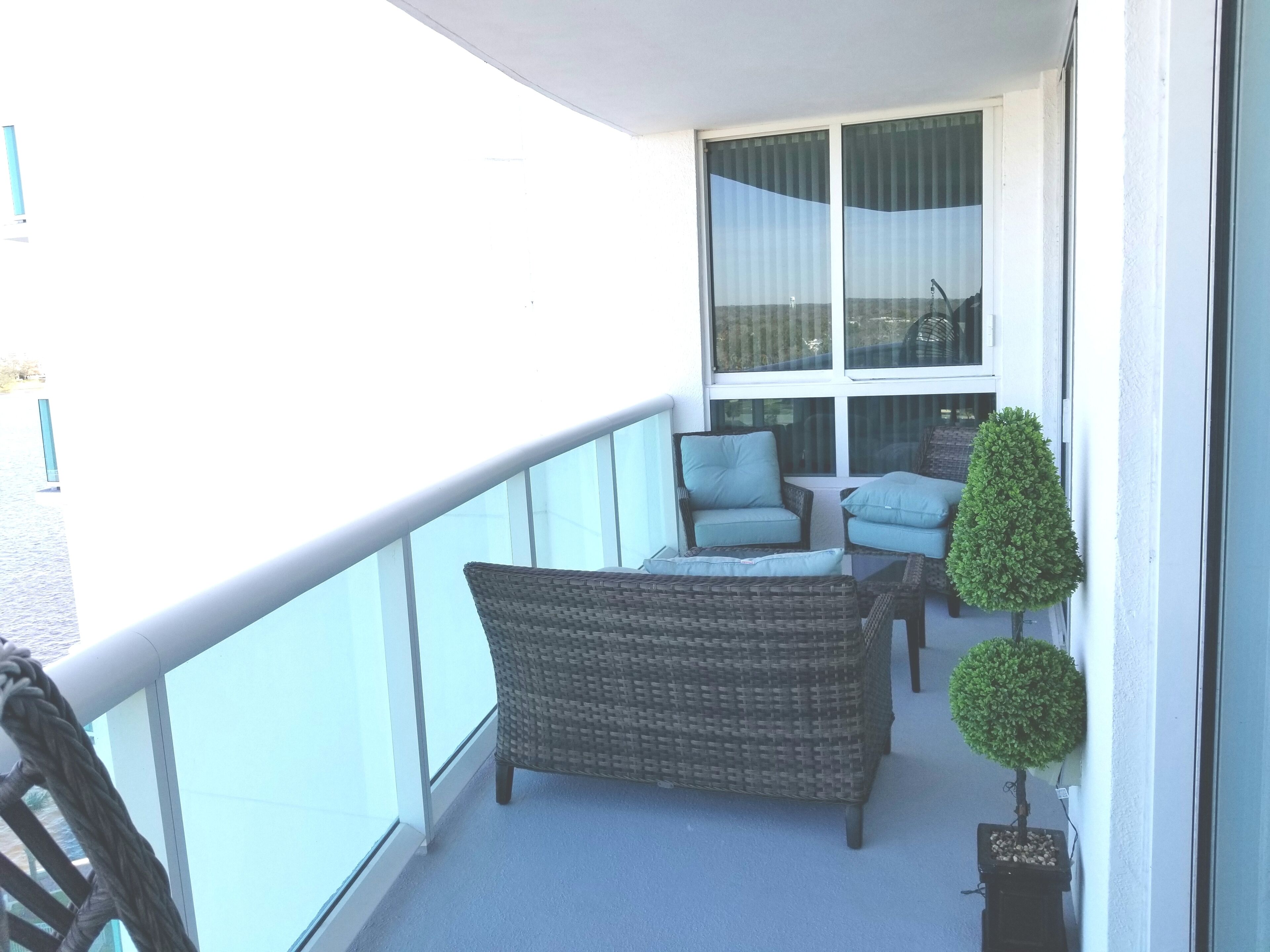 Un balcón con muebles de mimbre, una mesita y una planta en maceta.