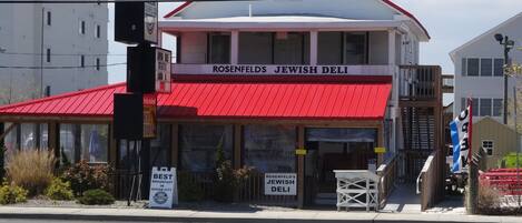 Ein zweistöckiges Gebäude mit rotem Dach und einem Schild, auf dem steht: 'Rosenthal's Jewish Deli'.