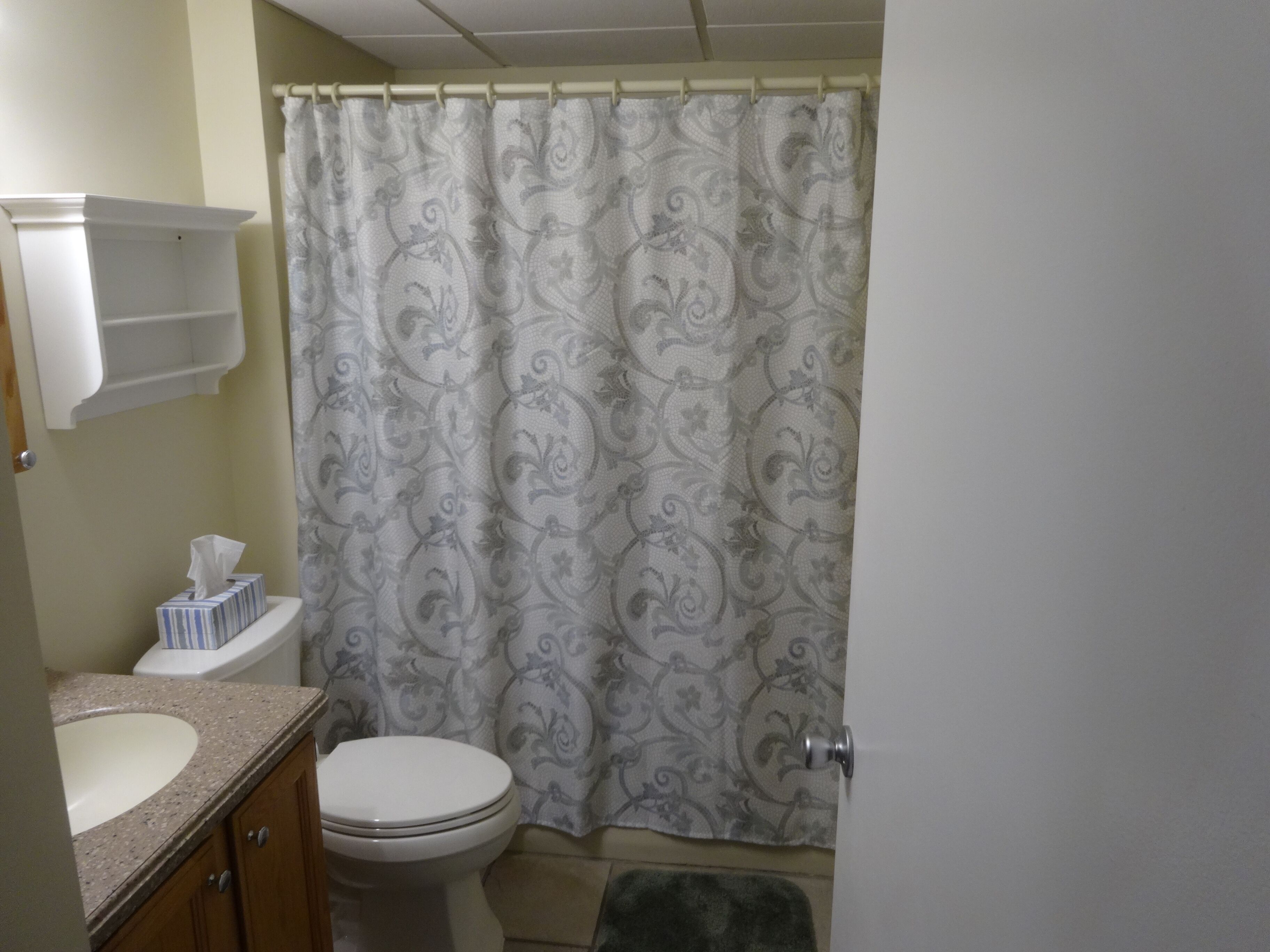Een badkamer met toilet, wastafel en douchegordijn met een bloemendesign.