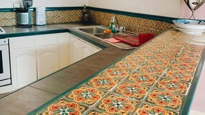 Una cocina con una encimera larga, un lavabo y una ventana con rejas decorativas de hierro.