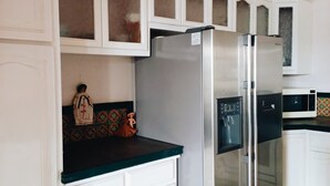Una cocina con armarios blancos, un refrigerador de acero inoxidable y un microondas.