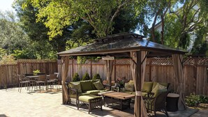 A covered patio area with outdoor furniture, including a sofa and chairs, and a small table. - Executive Vacation House Next to Ritz-Carlton in Half Moon Bay (Half Moon Bay)
