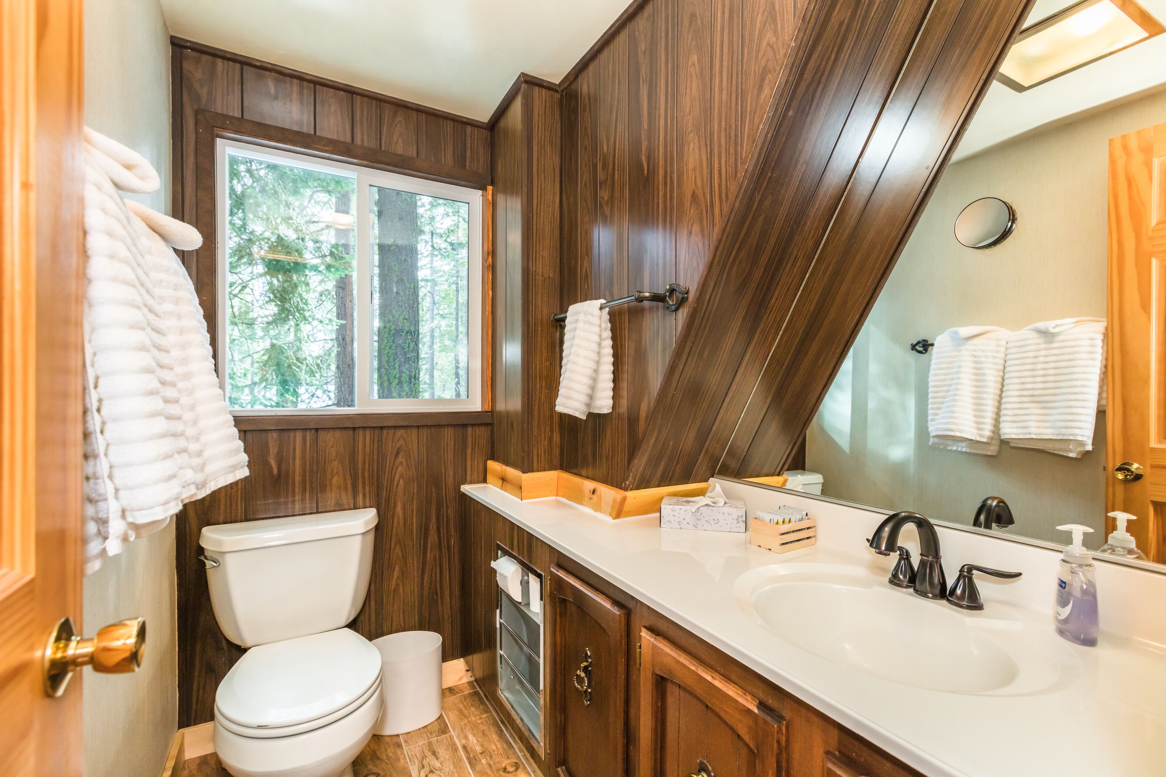 A bathroom with a toilet, sink, and mirror.
