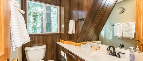 A bathroom with a toilet, sink, and mirror.