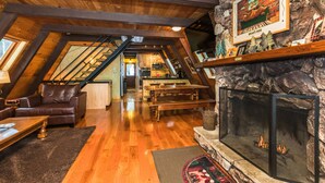 Een gezellige loft met een woonruimte, voorzien van een open haard, houten balken en een stenen muur.