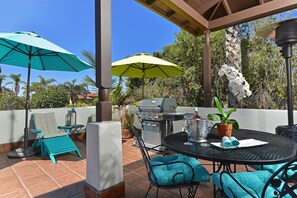 A patio with outdoor furniture, a grill, and umbrellas.