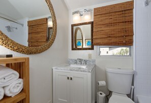 A bathroom with a white sink, a toilet, a mirror, and a shower.