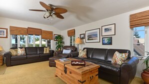 A living room with two dark leather sofas, a wooden coffee table, and a ceiling fan.