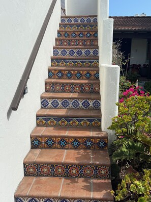 Eine Treppe mit farbenfrohen, gemusterten Fliesen, die zu einer weißen Tür führt.