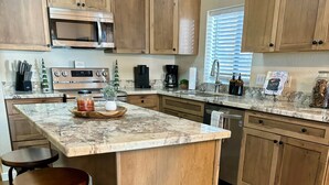 A kitchen with wooden cabinets, a granite countertop, a built-in oven, and a coffee maker. - SPECTACULAR MOUNTAIN BLUFF CABIN WITH LAKE VIEWS-CENTRAL AC! (Pinetop-Lakeside)