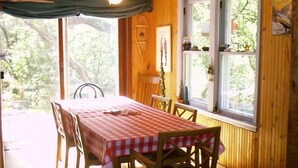 A dining area with a table set for four, wooden walls, and a window with a view of greenery. - Fly Fishing River Chalet, Fly Shop, Guides, Schools, & Kayaks! (River Falls)