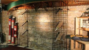 A stone wall with metal racks and a wooden shelf with items. - Fly Fishing River Chalet, Fly Shop, Guides, Schools, & Kayaks! (River Falls)