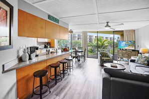 A modern hotel room with a kitchen, bar area, and seating space.