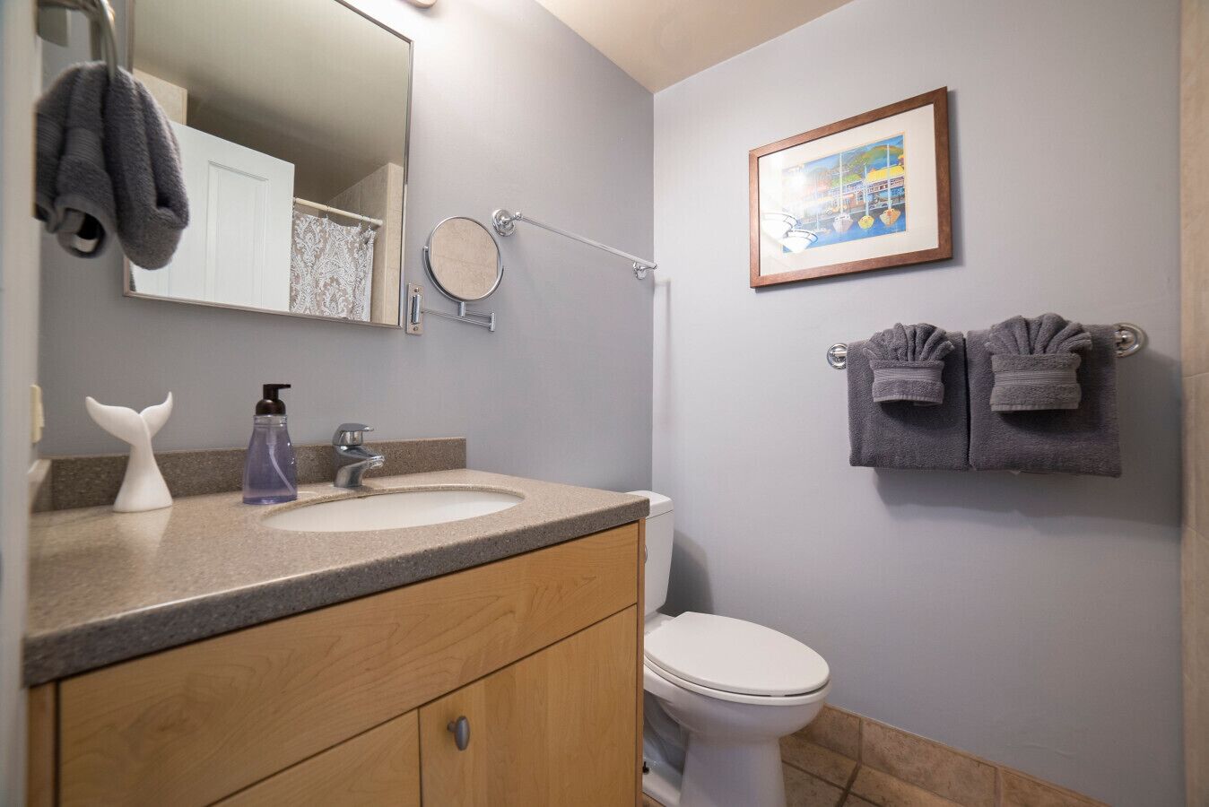 A bathroom with a sink, mirror, toilet, and towels.