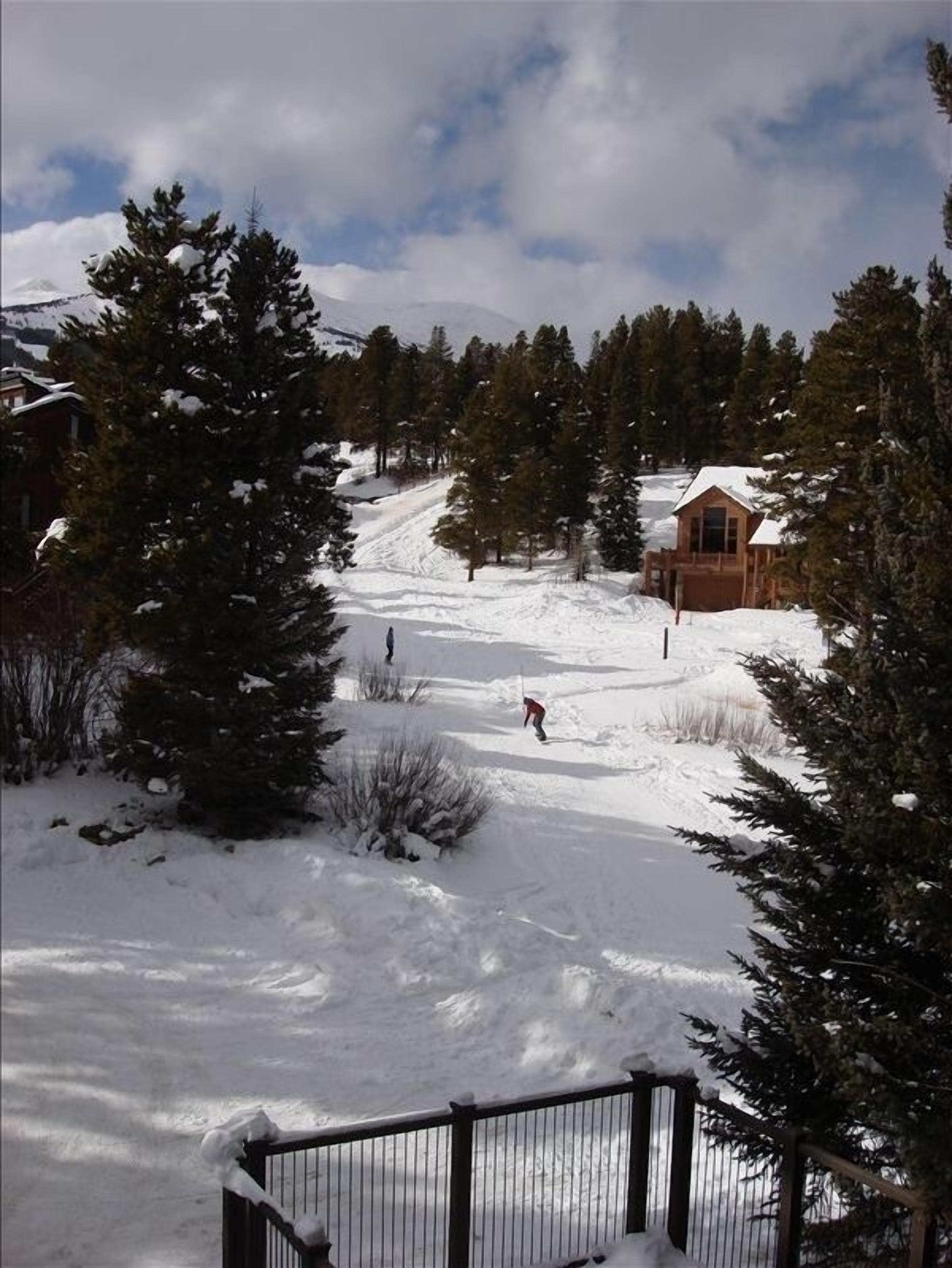 View from deck of 4 O'Clock Ski run w/snowboarders, peak 8, hot tub fence